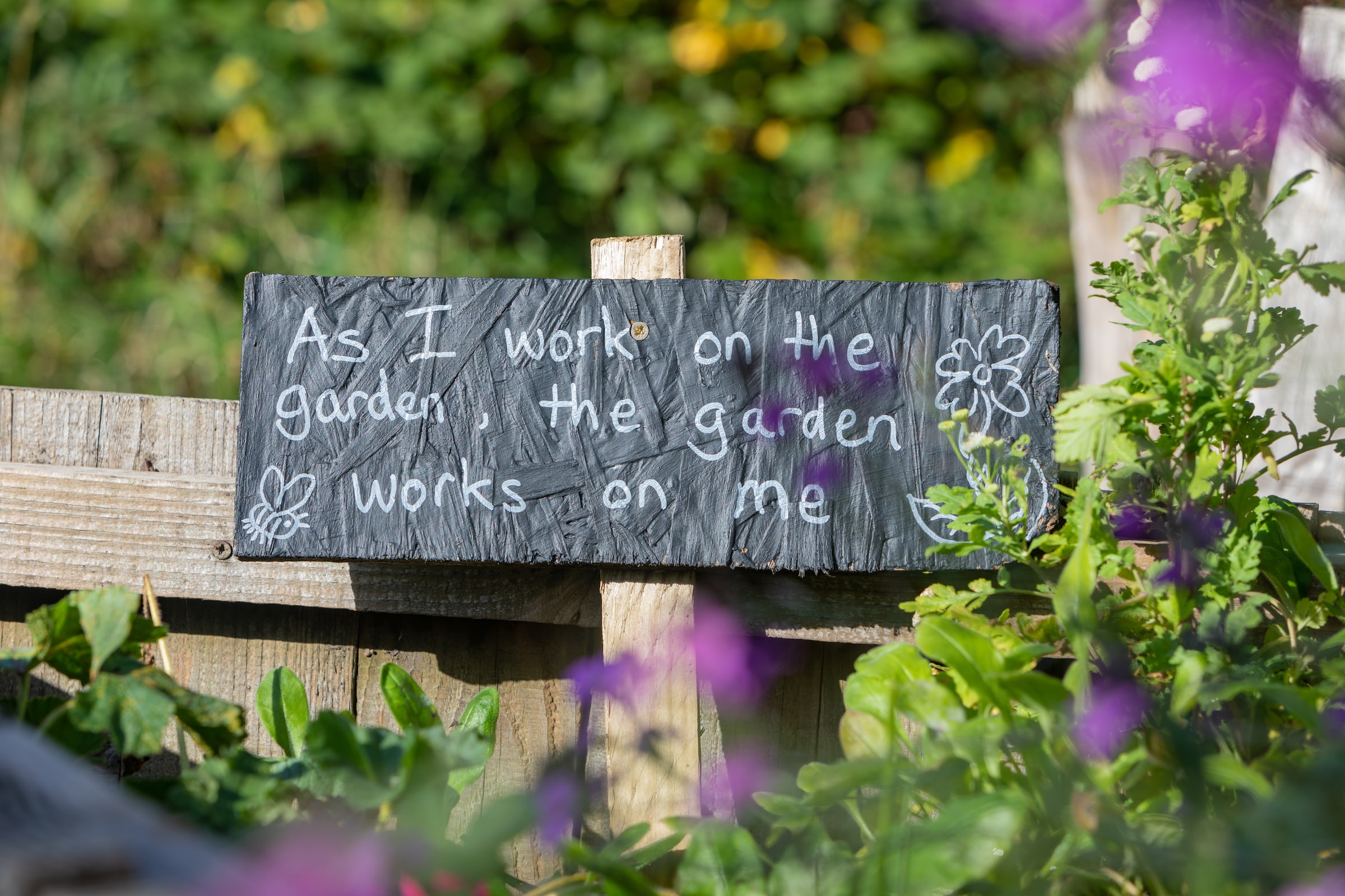 Garden sign that says As I work on the garden, the garden works on me